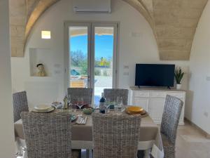 a dining room with a table with chairs and a television at Villa Chiara by salentoltremare in Corsano