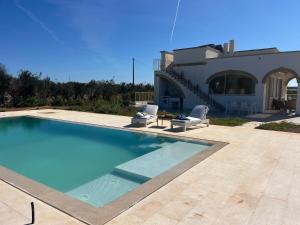 a swimming pool with two chairs and a house at Villa Chiara by salentoltremare in Corsano