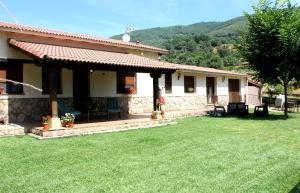 a house with a grass yard in front of it at Casa de la Senda in Candeleda