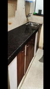 a kitchen with a black counter and a sink at Peaceful Stay at Microtek Greenburg EWS Located at Sec-86 Gurgaon Near NH8 IMT Manesar in Gurgaon