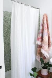 a white shower curtain hanging in a room with a plant at CoastalandCo in Evans Head +34 photos