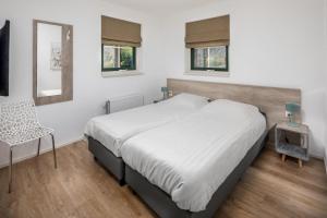 a bedroom with a bed and a chair and a mirror at Vennenhof Wellness Bungalow | 6 personen in Hooghalen +17 photos