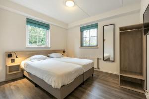 a bedroom with a large bed and two windows at Esdorp Bungalow | 6 personen in Hooghalen +25 photos