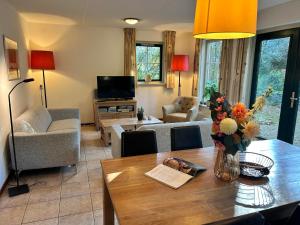 a living room with a table with flowers on it at Esdorp Bungalow | 6 personen in Hooghalen