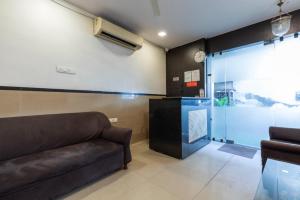 ムンバイにあるHotel Ajwaのソファと壁掛け時計のあるリビングルーム