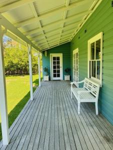a porch of a green house with a bench at Blue Pearl - Old Bar Holiday Rentals in Old Bar