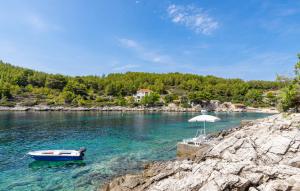 un bateau dans l'eau près d'une plage avec un parasol dans l'établissement Waterfront House Arnet by Villas Guide, à Potirna