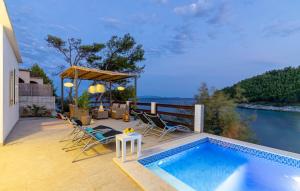 une terrasse avec une piscine et des chaises au bord de l'eau dans l'établissement Waterfront House Arnet by Villas Guide, à Potirna