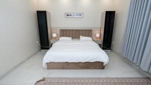 a bedroom with a large bed with white sheets and pillows at Cozy Escape in Dammam