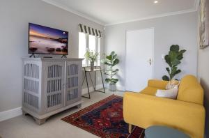 a living room with a tv and a yellow couch at LIMA HOUSE, Seaforth, Simon's Town in Simonʼs Town +7 photos
