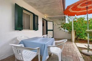 una mesa con sillas blancas y una sombrilla en el patio en Villaggio Vacanza Baia Falcone, en Vieste