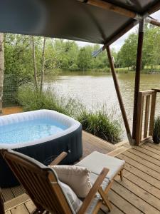 Un jacuzzi en una terraza con una silla y una sombrilla. en Teal Safari Tent, en Droitwich