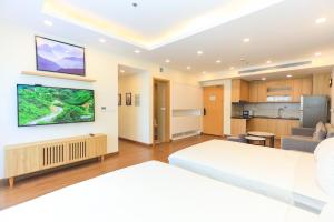 a bedroom with a large white bed and a kitchen at FLC SEA TOWER YẾN MINH Apartment in Quy Nhon