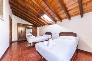 a bedroom with two beds and a wooden ceiling at Your retreat on the Asturian coast in Andrín