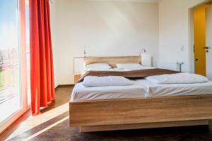 a bedroom with a bed with white sheets and red curtains at Ferienhauspark Asgard in Damp in Damp