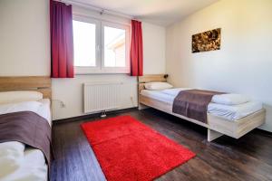 a bedroom with two beds and a red rug at Ferienhauspark Asgard in Damp in Damp