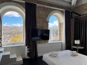 a bedroom with two arched windows and a tv at Palazzo Franceschini in Cascia