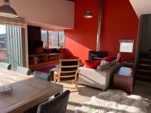 a living room with red walls and a couch and a table at Perisher stand alone chalet - available all year in Perisher Valley