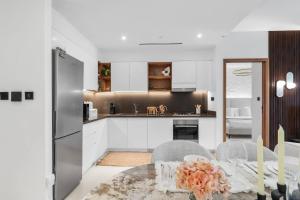 a kitchen with white cabinets and a dining table at Novity Luxury Vida Marina 2BR Sea View 40th Floor in Dubai