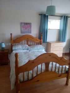 a large wooden bed in a bedroom with blue curtains at Bun An Coirin in Clonbur