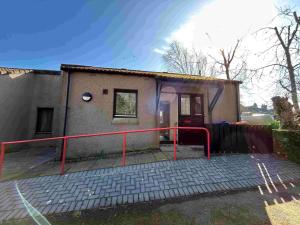 a small house with a red railing in front of it at Two bedroom cottage in Lumsden - Contractors in Huntly
