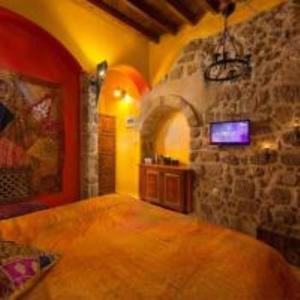 Cette chambre est dotée d'un mur en pierre et d'une télévision murale. dans l'établissement boutique hotel, à Mesochórion