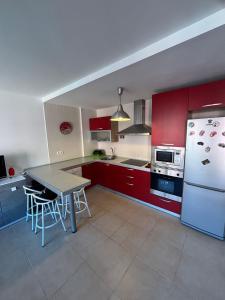 a kitchen with red cabinets and a table and a refrigerator at El Mocan Apartment Palm Mar in Palm-mar