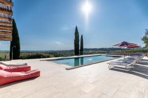 a swimming pool with a red couch and umbrellas at La Fornace - Charm and modern villa in Tuscany in Campagnatico