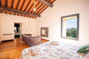 a bedroom with a bed and a chair and a window at La Fornace - Charm and modern villa in Tuscany in Campagnatico