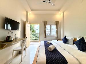 a bedroom with a bed and a desk and a window at Zuna Stayz Tapovan Rishikesh in Rishīkesh