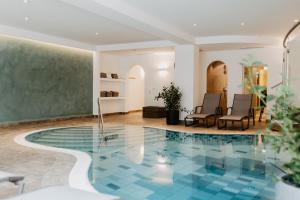 a swimming pool with two chairs and a table at Hotel Hubertus in Lofer +21 photos