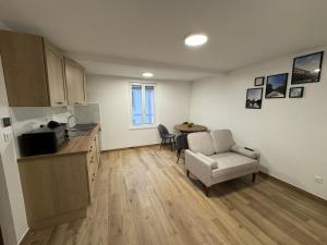 a kitchen and a living room with a couch and a chair at La Tranquillité Citadine in Schiltigheim