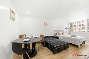 a bedroom with a table and a bed and a table and chairs at MetaWise BnB Bright 1Bed Studio Near Kings Cross in Sydney