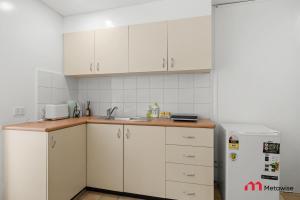 a kitchen with white cabinets and a sink and a refrigerator at MetaWise BnB Bright 1Bed Studio Near Kings Cross in Sydney