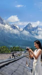 een vrouw in een witte jurk staand op een dak met bergen bij 37 Courtyard(Baisha Ancient Town) in Baisha