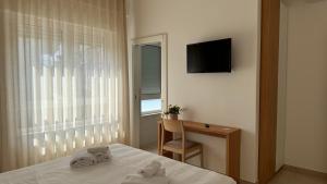 een slaapkamer met een bed, een bureau en een televisie bij Estelle in Bari