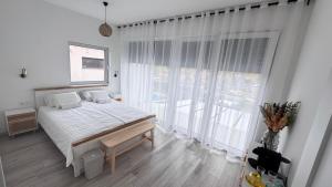 a white bedroom with a bed and a large window at EtyekZen in Etyek