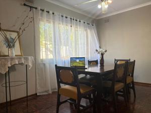 a dining room table with chairs and a laptop on it at Mitchell Guest House Golf Road in Pietermaritzburg +6 photos