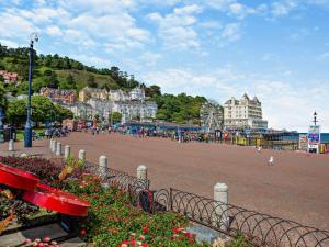 a city street with buildings and a park with flowers at 4 Bed in Llandudno 89703 in Deganwy
