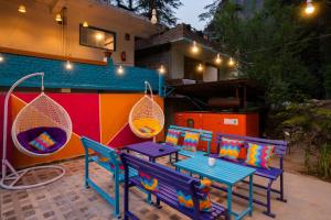 a patio with two benches and a table with pillows at goSTOPS Kasol in Kasol