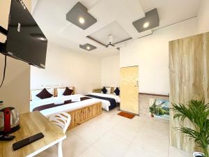 a hotel room with two beds and a flat screen tv at Zuna Stayz Tapovan Rishikesh in Rishīkesh