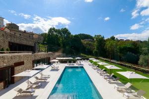 a swimming pool with lounge chairs and umbrellas at Borgotufi Albergo Diffuso in Castel del Giudice
