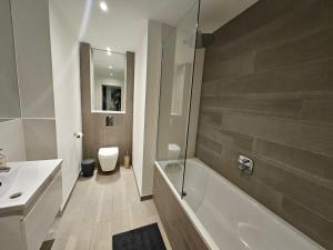 a bathroom with a tub and a sink and a toilet at Luxury 2 double bedroom Apt in the heart of Purley in Purley