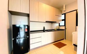 eine Küche mit einem schwarzen Kühlschrank und weißen Schränken in der Unterkunft Greenfield Regency by Antlerzone in Johor Bahru