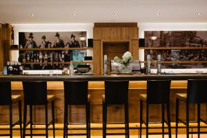 a bar in a restaurant with black bar stools at Hotel Hubertus in Lofer