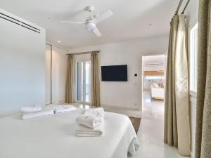 a white bedroom with two beds and a flat screen tv at Villa Raphael - Luxury and Serenity in Paros in Naousa +60 photos