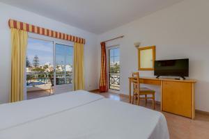 ルースにあるLuz Bay Hotelのベッドとパソコン付きの机がある寝室