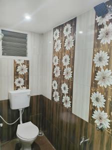 a bathroom with a toilet and flowers on the wall at Miracle Stay in Madurai