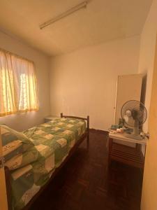 a bedroom with a bed and a fan and a table at Sweet home Beverly hills in Penampang