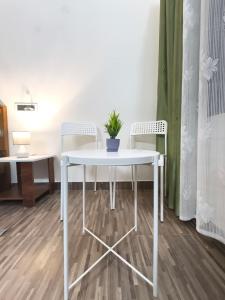 a white table with two chairs and a potted plant on it at Flickstays Elara in Bangalore